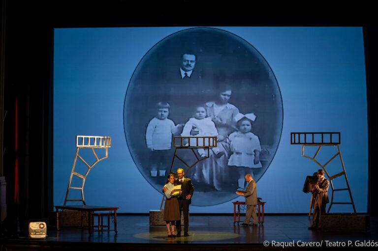 Fotografía familiar antigua proyectada en un óvalo sobre el fondo del escenario, con los intérpretes debajo. Foto: Raquel Cavero / Teatro Pérez Galdós