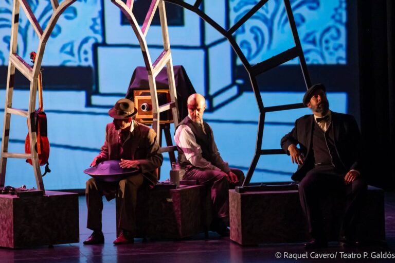 Varios personajes sentados sobre bloques bajo un gran arco dibujado, con fondo de azulejos azules. Foto: Raquel Cavero / Teatro Pérez Galdós