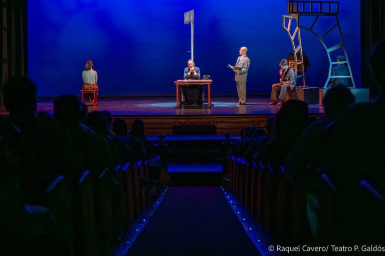 Escena vista desde la sala, con las cabezas del público recortadas ante el escenario iluminado. Foto: Raquel Cavero / Teatro Pérez Galdós