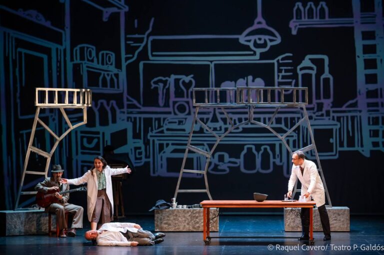 Plano general del laboratorio dibujado, con un cuerpo tendido en el suelo y las batas blancas alrededor. Foto: Raquel Cavero / Teatro Pérez Galdós