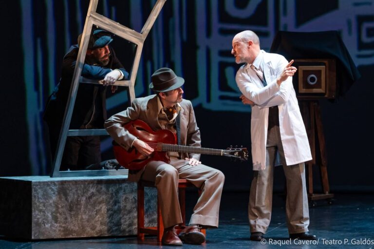 El guitarrista sentado toca mientras un intérprete de bata blanca le habla de pie. Foto: Raquel Cavero / Teatro Pérez Galdós