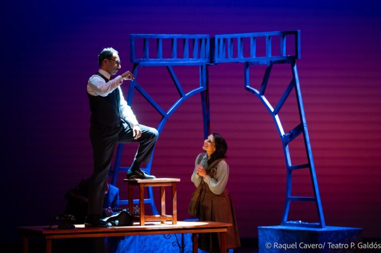 Un intérprete subido a una banqueta se dirige a una compañera que lo mira desde abajo. Foto: Raquel Cavero / Teatro Pérez Galdós