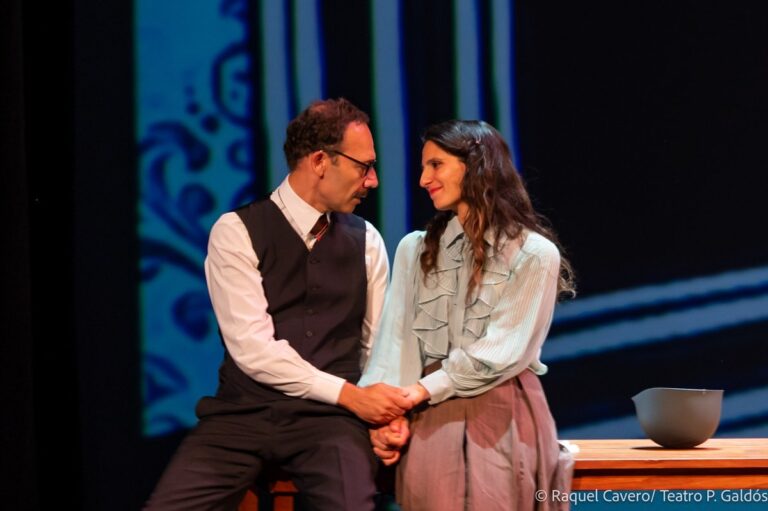 Dos intérpretes sentados muy juntos bajo luz azul, el de chaleco y ella de blusa blanca. Foto: Raquel Cavero / Teatro Pérez Galdós