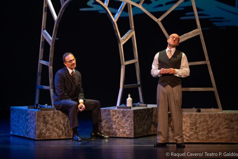 Dos intérpretes bajo el arco de la escenografía: uno sentado en un bloque y otro de pie. Foto: Raquel Cavero / Teatro Pérez Galdós