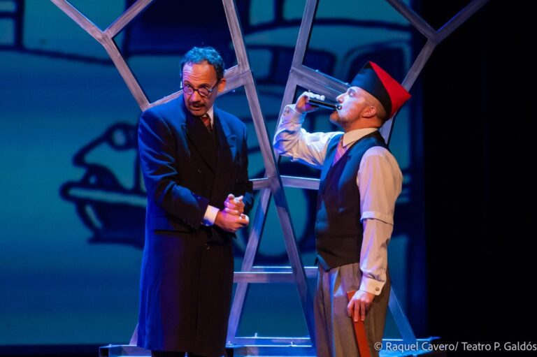 Un intérprete sostiene a otro, con gorro rojo, mientras bebe. Foto: Raquel Cavero / Teatro Pérez Galdós