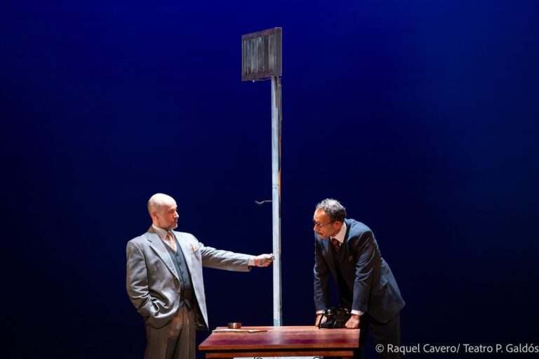 Dos intérpretes junto al poste del altavoz, uno con el brazo extendido hacia el otro. Foto: Raquel Cavero / Teatro Pérez Galdós