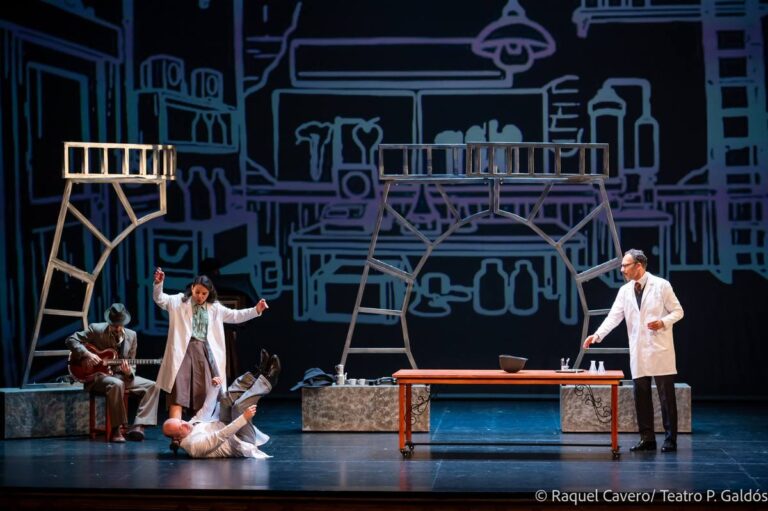 Escena de laboratorio con un personaje caído en el suelo y otros dos en pie. Foto: Raquel Cavero / Teatro Pérez Galdós